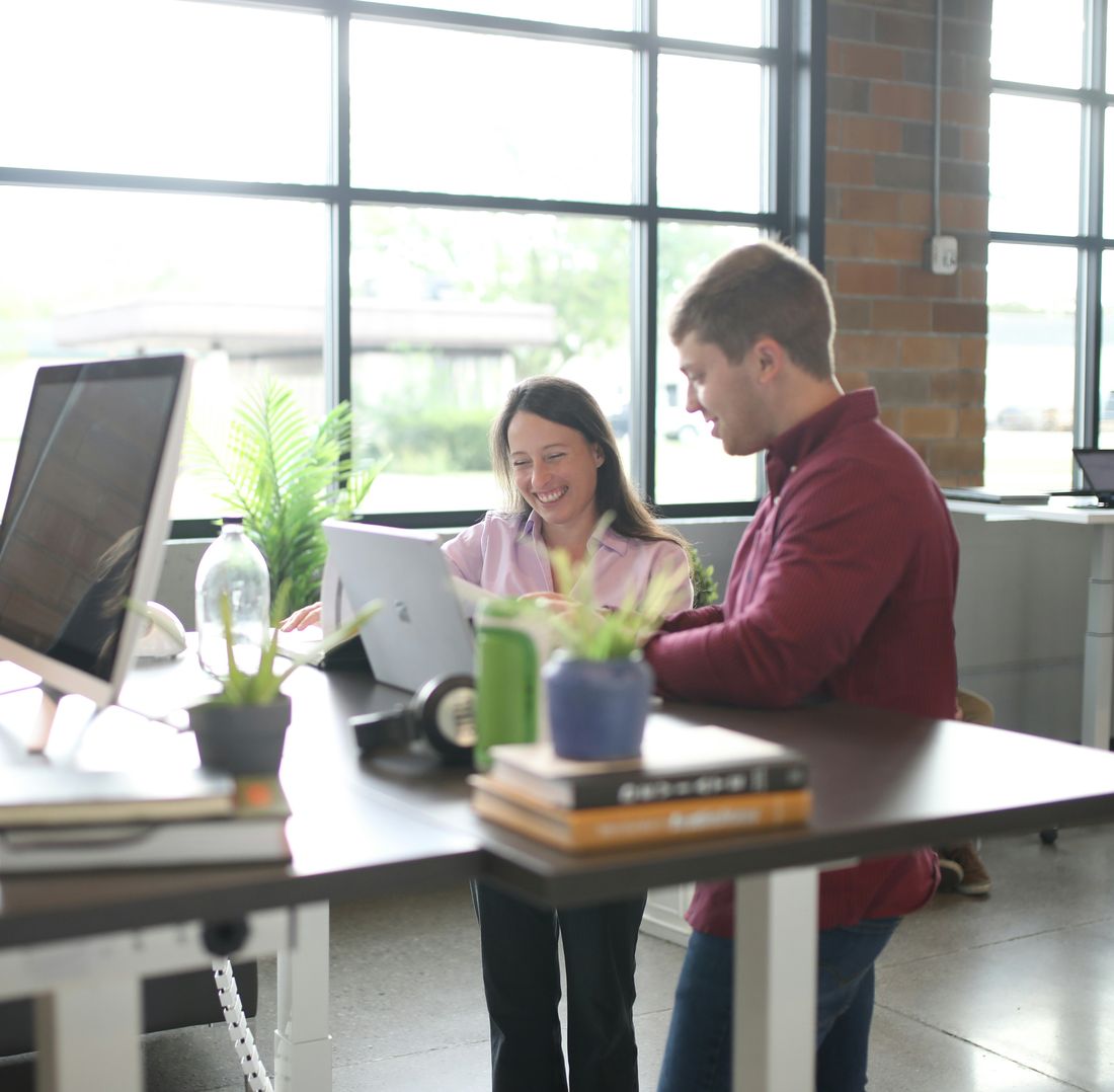 Colleagues working together at a shared desk in a bright office